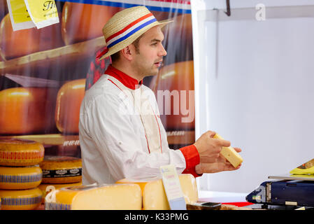 Kristiansand, Norvegia - 16 agosto 2017: Travel documentario di strada del mercato. Olandese fornitore Cheeseman holding e mostrando un pezzo di formaggio. Foto Stock