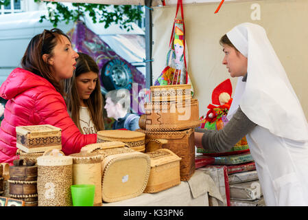 Kristiansand, Norvegia - 16 agosto 2017: documentario di viaggio della vita quotidiana nella città. Donna vendita di corteccia di betulla le caselle in strada del mercato. Qui a parlare Foto Stock