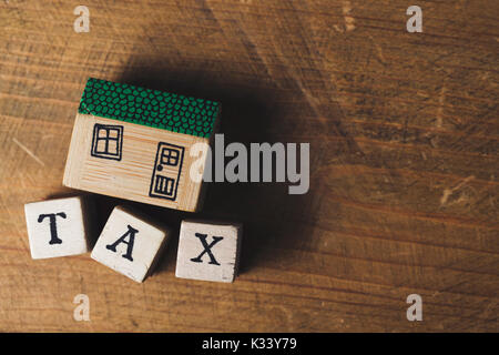 Modello di casa con tasse parola fatta da blocchi di legno. Home Concetto di finanza Foto Stock