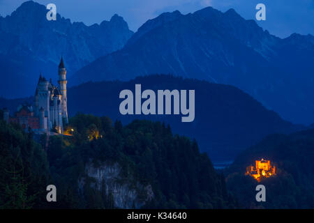 Germania. Notte estiva in Baviera. Luci di due castelli di Neuschwanstein e Hohenschwangau contro lo sfondo delle montagne boscose Foto Stock