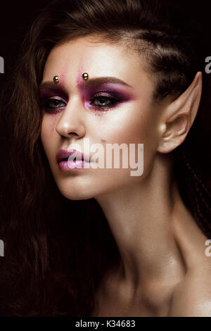 Bruna ragazza con un creative trecce di acconciatura, arte make-up e la Elf le orecchie. Bellezza viso. Foto Stock