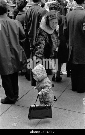 Madre e figlio 1970 anni Regno Unito. Il bambino ha preso la borsa che aveva messo a terra mentre era in fila per guardare una sfilata. Londra, Inghilterra 1975 HOMER SYKES Foto Stock