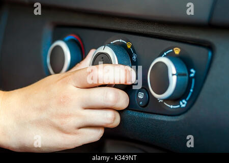 Primo piano di una mano umana auto ruotando il comando della temperatura, la profondità di campo di una shot Foto Stock