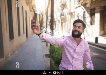La foto di un giovane uomo seduto sulla strada di pentola e tenendo lo stesso una foto. Foto Stock