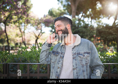 Una foto di giovani, uomo bello avere belle conversazioni telefoniche e ridere. Foto Stock