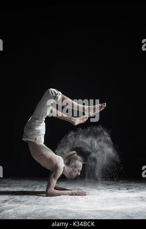 Yoga flessibile man mano facendo equilibrio asana vrischikasana. Foto Stock