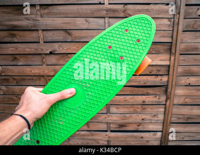 Maschio lato tenendo un penny verde pensione in uno skatepark. Foto Stock