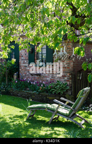 Sedia a sdraio in un accogliente giardino dietro la casa Foto Stock