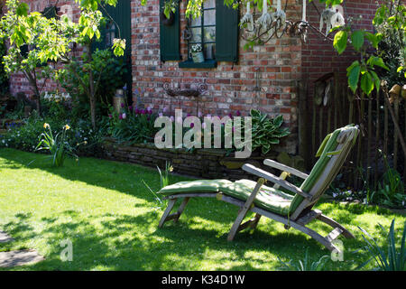 Sedia a sdraio in un accogliente giardino dietro la casa Foto Stock