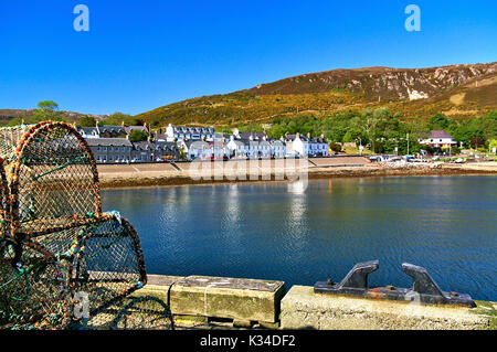 Quay con pesce trappole e bollard in primo piano e bianco case sul lungomare in background Foto Stock