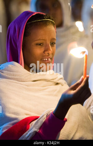 Giovani femmine pellegrino tenendo un cero per indicare la risurrezione, nel cortile di Bet Medhane Alem chiesa, durante le preghiere in Etiopia Sabato di Pasqua, Lalibela, Etiopia Foto Stock