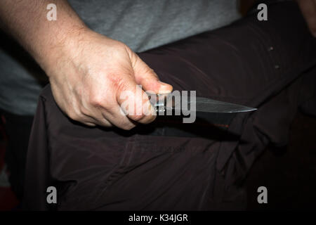 Primo piano di un giovane uomo di mano, tenendo un coltello, per attaccare, Foto Stock