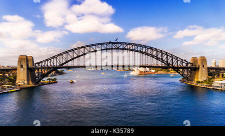 Vista in elevazione laterale del Ponte del Porto di Sydney il collegamento di sponde del porto di Sydney in una giornata di sole da sopra l'acqua. Foto Stock