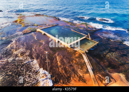 Remote roccia isolata piscina off Mona Vale beach a marea alta con il nuotatore onde dell'Oceano Pacifico costa di Sydney. Foto Stock