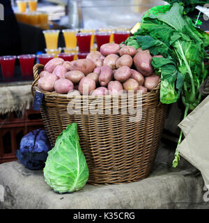 Patate fresche in un cesto di vimini dal nuovo raccolto in sacchi di carta sono sul mercato Foto Stock