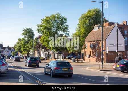 Cars driving lungo viale alberato High Street nella storica città mercato di Baldock Hertfordshire Nord, England, Regno Unito Foto Stock