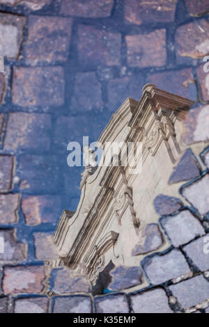 Chiesa di San Francesco, Italiano tradizionale di chiesa riflessa in una pozzanghera sulla pavimentazione / strada di ciottoli Foto Stock