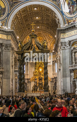 I visitatori all'interno della basilica di san Pietro, altare con berninis baldacchino e cathedra petri e gloria in background Foto Stock