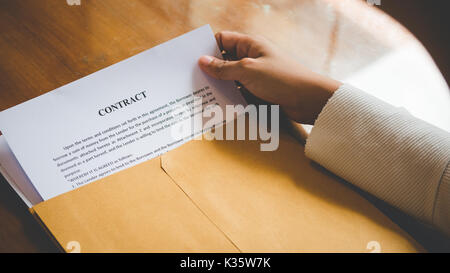 Le donne stanno aprendo una busta documento circa la firma di un contratto per il business e firmare il contratto concetto,stile vintage Foto Stock