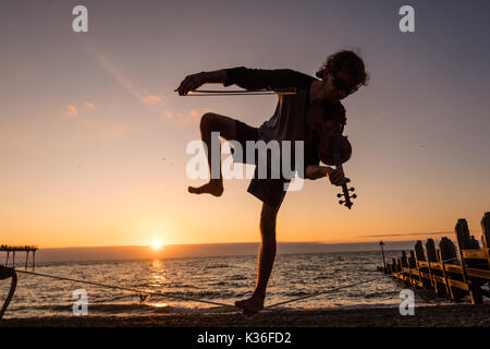 Aberystwyth Wales UK, venerdì 01 settembre 2017 UK meteo: 21 anni studente post-laurea ALEX FREEMAN, si prende una pausa dalla sua fisica del master in studi a suonare il violino e il bilanciamento su un lasco-linea come il sole tramonta dietro di lui su Cardigan Bay in Aberystwyth, alla fine di una luminosa e soleggiata primo giorno di settembre foto © Keith Morris / Alamy Live News Foto Stock