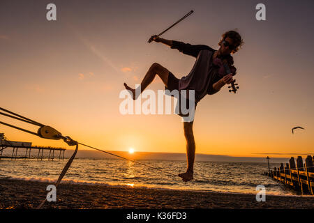 Aberystwyth Wales UK, venerdì 01 settembre 2017 UK meteo: 21 anni studente post-laurea ALEX FREEMAN, si prende una pausa dalla sua fisica del master in studi a suonare il violino e il bilanciamento su un lasco-linea come il sole tramonta dietro di lui su Cardigan Bay in Aberystwyth, alla fine di una luminosa e soleggiata primo giorno di settembre foto © Keith Morris / Alamy Live News Foto Stock