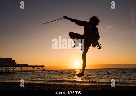 Aberystwyth Wales UK, venerdì 01 settembre 2017 UK meteo: 21 anni studente post-laurea ALEX FREEMAN, si prende una pausa dalla sua fisica del master in studi a suonare il violino e il bilanciamento su un lasco-linea come il sole tramonta dietro di lui su Cardigan Bay in Aberystwyth, alla fine di una luminosa e soleggiata primo giorno di settembre foto © Keith Morris / Alamy Live News Foto Stock