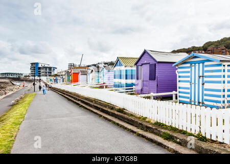 Multicolore di cabine sulla spiaggia, di fronte al mare sulla passeggiata di Condino, Devon, Inghilterra, Regno Unito, behinf un basso bianco Picket Fence Foto Stock