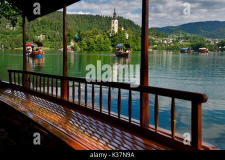 Vista di Bled Isola Assunzione di Maria la Chiesa del pellegrinaggio e del legno barca Pletna vogatori canottaggio turisti sul Lago di Bled Slovenia Foto Stock