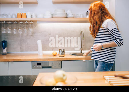 Donna mantenendo la cucina ordinata e pulita Foto Stock