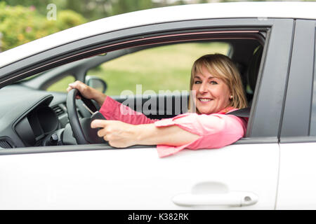 Felice e sorridente senior donna in nero auto Foto Stock