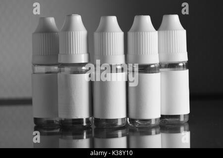 Isolato e bottiglie di liquido per dispositivi vaping, e sigaretta, sigaretta elettronica, su uno sfondo nero. Foto Stock