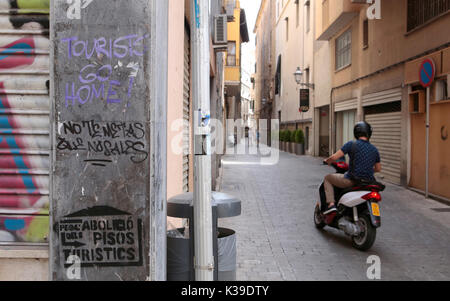 Dipinti murali la lettura "turisti vanno a casa' e abbassare in catalano "abolizione affitto vacanze alloggio" sono illustrati in una via centrale il centro di Palma in Foto Stock