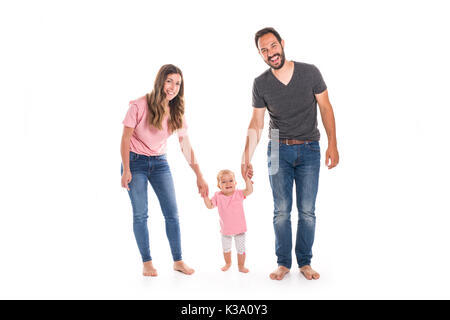 Coppia di giovani genitori aiutare i loro bambini a fare i primi passi sul pavimento nella loro casa Foto Stock