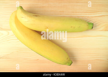 Vista dall'alto di due giallo vivace banane mature sul tavolo di legno Foto Stock