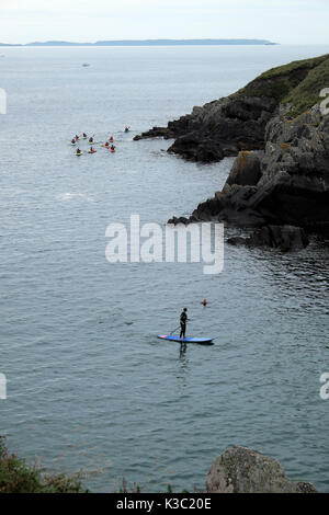 Kayakers e uomo su paddleboard in mare al Porto di Porthclais in estate vicino a Saint David in Pembrokeshire West Wales UK KATHY DEWITT Foto Stock