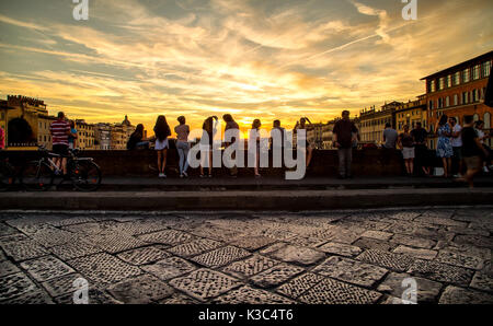 Tramonto sulla scena uno dei tanti antichi ponti in Firenze con i turisti il floccaggio Foto Stock