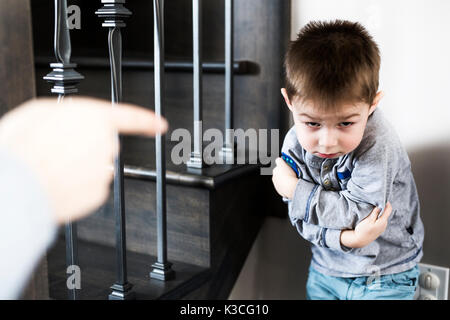 Ragazzo seduto da solo appoggiata sulla parete con il padre pugno. Foto Stock