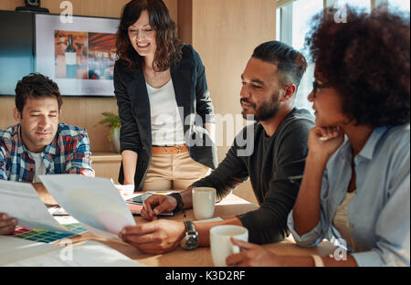 Un gruppo di giovani persone di affari e designer guardando alla tavolozza dei colori. Il brainstorming Team in sala riunioni con i campioni di colore. Foto Stock