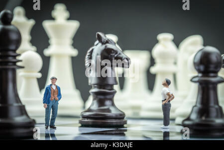 Gli uomini miniatura all'interno di un gioco di scacchi, concept Foto Stock