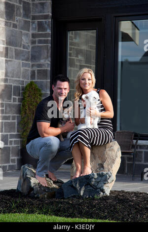 Giovane Azienda i loro cani all'aperto davanti alla loro casa Foto Stock