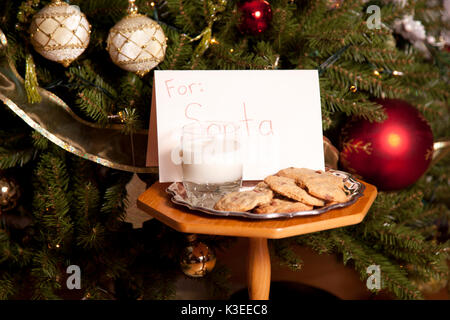 Latte e biscotti nella parte anteriore di un albero di natale per santa. Foto Stock