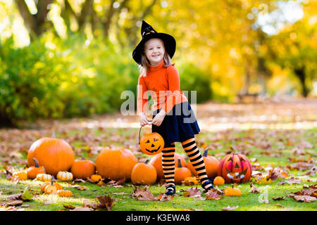 I bambini con la zucca di Halloween. Bambina in costume da strega e hat giocando in autunno park. Bambino di Halloween dolcetto o scherzetto. Kid trucco o trattare. Foto Stock