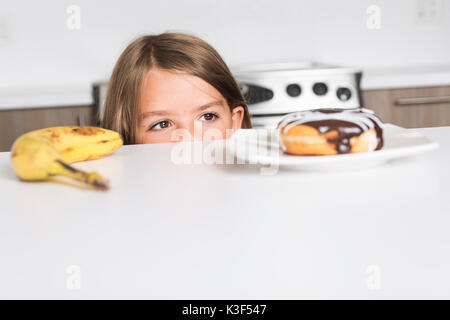 Kid scegliendo tra ortaggi sani e gustosi dolci Foto Stock