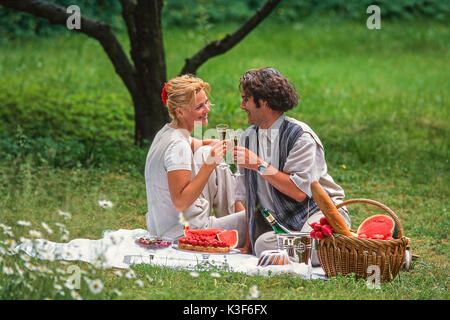 Giovane al picnic sollevando il vetro con vino spumante Foto Stock