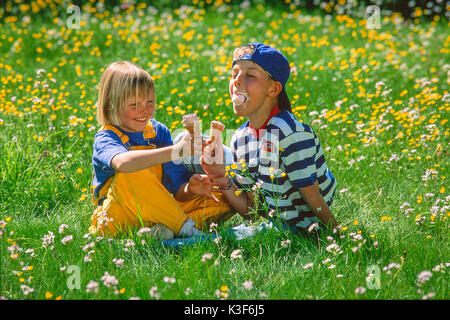 I bambini mangiano il ghiaccio nel prato di primavera Foto Stock