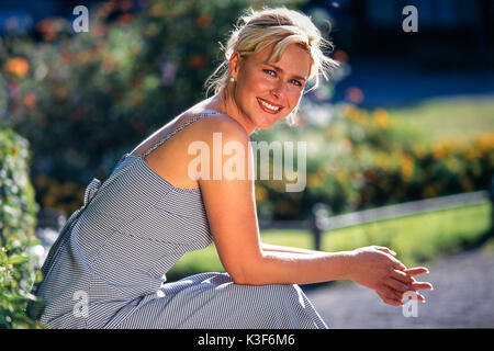 Sorridente giovane donna bionda su un parco-Panchina Foto Stock