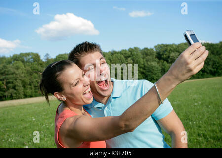 Coppia giovane prende una foto di loro stessi con il cellulare Foto Stock