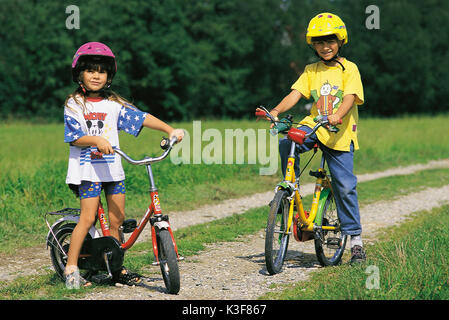 Due bambini in bicicletta su un vicolo del paese Foto Stock