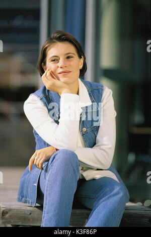 Sorridente giovane donna si appoggia sulle sue ginocchia Foto Stock