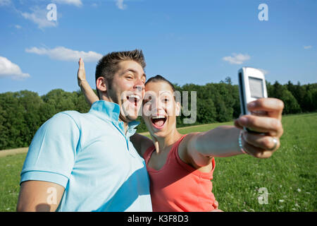 Coppia giovane prende una foto di loro stessi con il cellulare Foto Stock